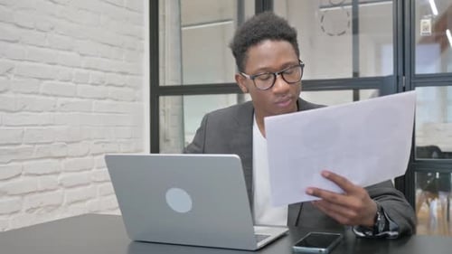 Young Adult Working on Laptop with Documents