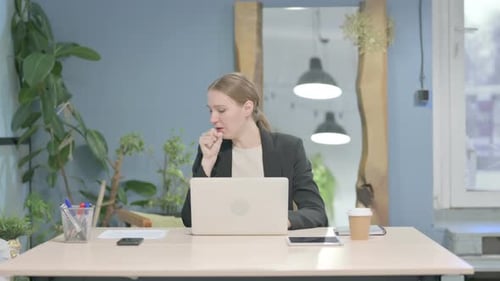 Woman Coughing at Desk with Laptop Indoors
