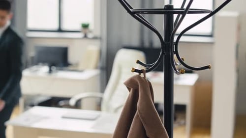 Young Adult Taking Overcoat off Coat Rack at Office