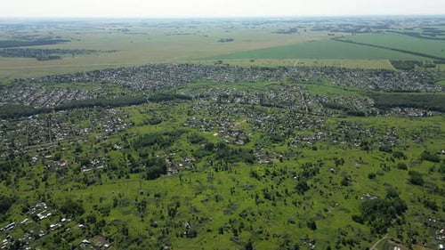 Perspectiva aérea de drone capturando uma paisagem verdejante, revelando um assentamento compacto em meio a um verde exuberante