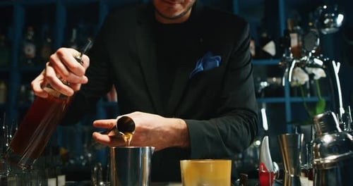 A professional bartender is preparing an alcoholic cocktail with ice cubes to customers at the bar