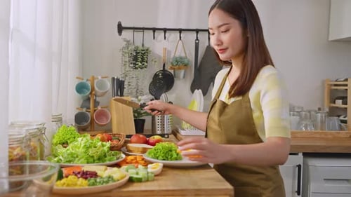 Woman in Kitchen Chopping Cucumber for Salad
