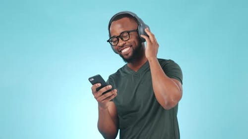 Headphones, phone and young black man in a studio listening to music, album or playlist