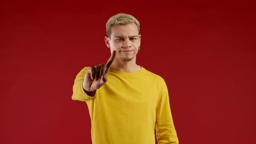 Young Adult Gesturing 'No' on Red Background