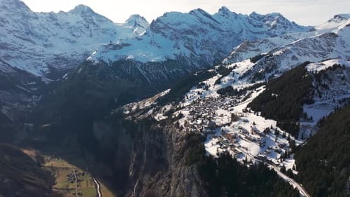 Aerial view of small snowy Switzerland village near steep mountain edge