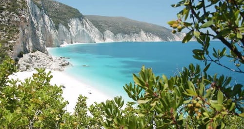 Secluded Fteri beach on Keflaonia Island, Greece. White rocks and blue lagoon surrounded by green fo