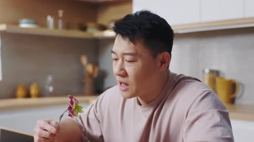 Man Eating Salad in Bright Kitchen