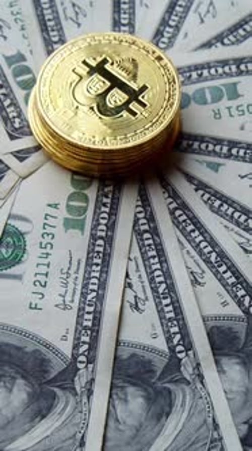 Gold Bitcoin Coins Stacked on One Hundred Dollar Bills