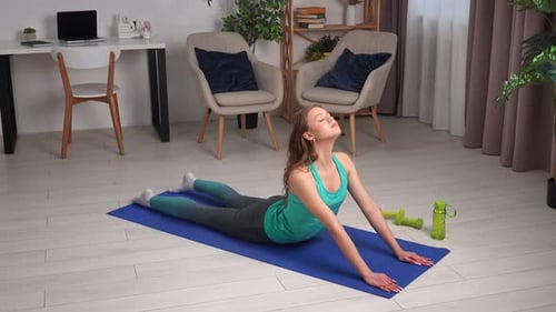 Young Woman Doing Yoga on Blue Mat at Home