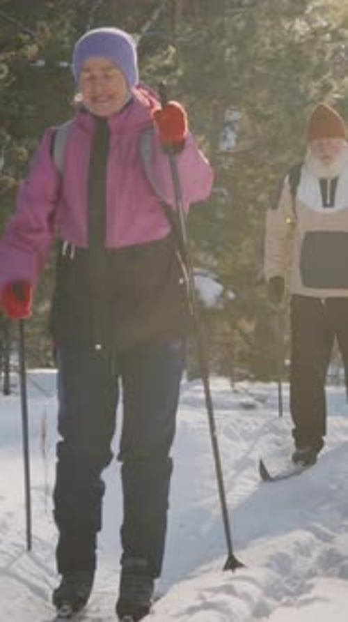Cheerful Elderly Couple Skiing Together in Winter Forest