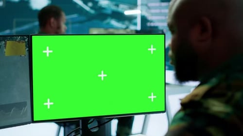 Military men watch green screen computer monitors