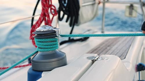 Young Man Captain Operates and Controls a Sailboat During a Journey By Sea in Winter Time in