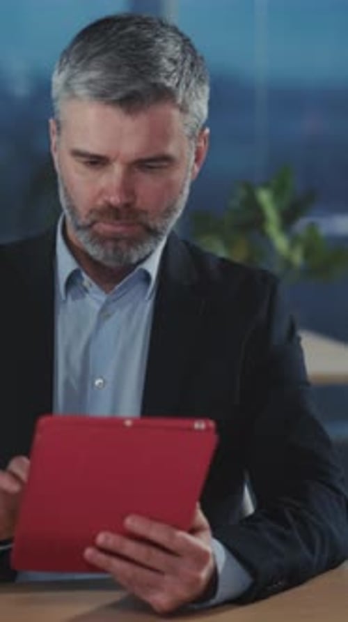 Skilled Executive Examines Reports on Digital Device Within Calm Office Setting with Lighting and