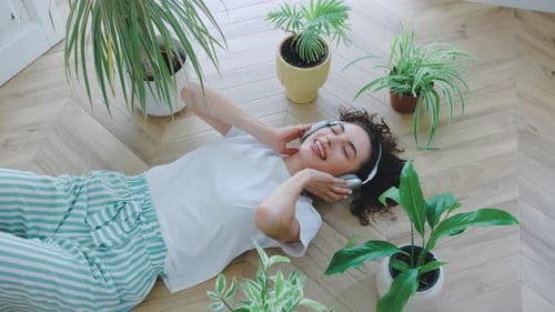 Woman with Headphones Lying Amongst Potted Plants