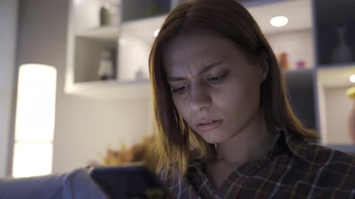 Crying young girl texts with her boyfriend on the phone.