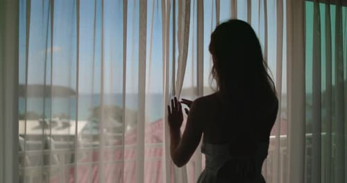 Woman Gazing Out Window at Ocean