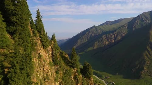 Aerial view flying over a ridge to reveal a picturesque mountain valley in Kyrgyzstan.