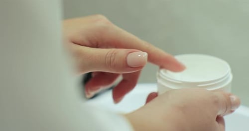 Closeup of Woman Hold Jar with Lifting Cream in Hands and Applying on Body for Smooth Healthy Skin