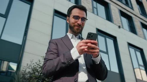 Smiling Man Using Smartphone Outside Office Building