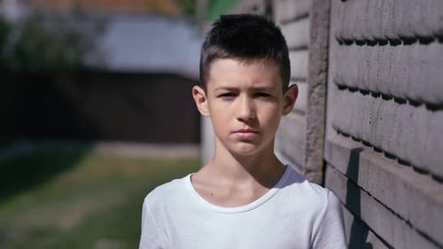 Young Person Against Concrete Wall Looking at Camera