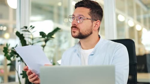 Focused Businessman Analyzing Documents and Reflecting in Office