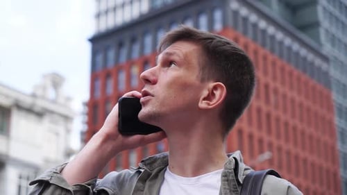 Ein junger Mann, der am Telefon spricht. Nahaufnahme. Eine belebte Stadtstraße