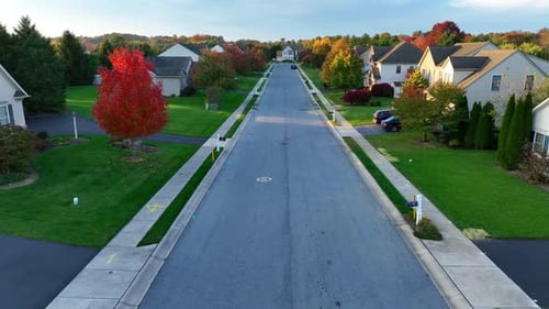 Autumn in an American suburb. Aerial shot above neighborhood street lined by houses, homes, and fall