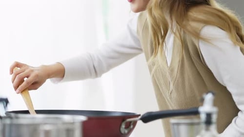 Woman Cooking and Testing Food in Kitchen