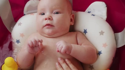 Mother Bathes Her Baby in Pink Bathtub Top View