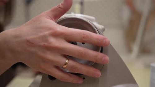 Closeup of Seamstress Hands Winding Bobbin Thread on Sewing Machine in Workshop Preparing