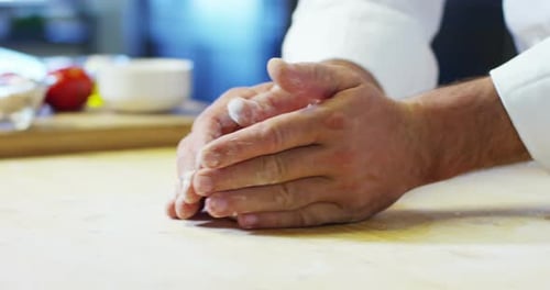Close up of a baker kneading with his hands to prepare the bread to put in the oven. Concept of: a