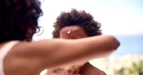 Woman Applies Sunscreen to Smiling Child on Beach