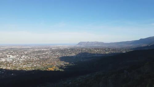 Drohnenaufnahme mit Stadt, Bergen und Meer im Hintergrund an einem Sommertag