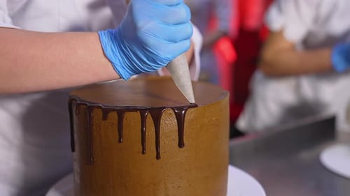 Decoration of cake with liquid chocolate. Melted chocolate flowing down from cake. Close up.