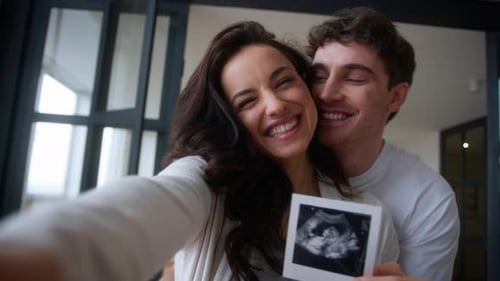 Young Couple Holding Baby Sonogram