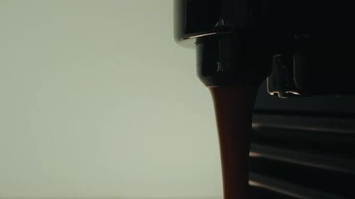 Close-up of espresso coffee brewing in a kitchen, capturing the liquid flowing from the