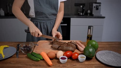 Woman Slices Bread with Knife in Modern Kitchen