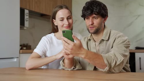 Young Couple Using Smartphone Together in Kitchen