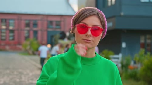Closeup Portrait of Friendlylooking Young Woman in Green Sweatshirt Smiling to Camera in Background