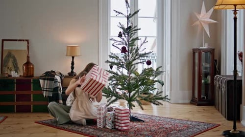 Mother and Daughter by Christmas Tree with Gifts