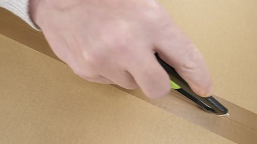 Opening a brown cardboard box with a box cutter