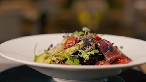 A close-up of a salad with avocado jamon and cherry tomatoes prepared in the professional kitchen