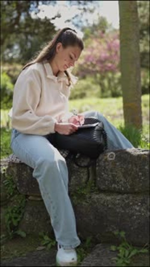 Young Woman Writing Outdoors in a Park