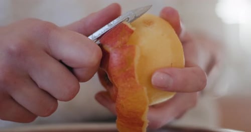 Hands peeling a red apple
