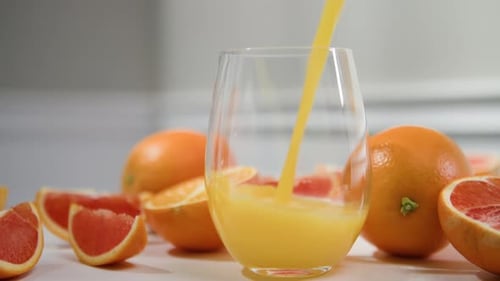 Pouring Fresh Orange Juice into Glass with Fruit