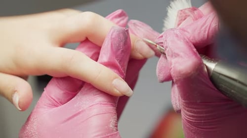 Close Up Nail Technician Using Electric File on Fingernail Wearing Pink Gloves