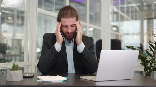 Stressed Man with Headache at Office Desk
