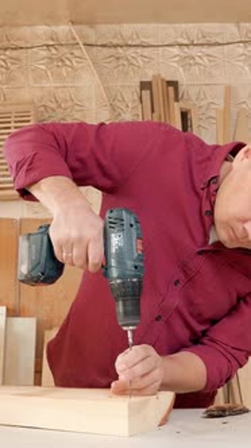 Skilled Carpenter Using Electric Drill to Assemble Wooden Furniture in a Workshop Showcasing