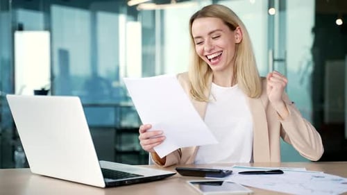 Excited Young Woman Celebrating Success in Office