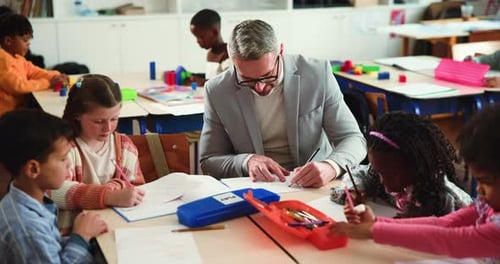 Elementary School Children Learning With Teacher In Classroom